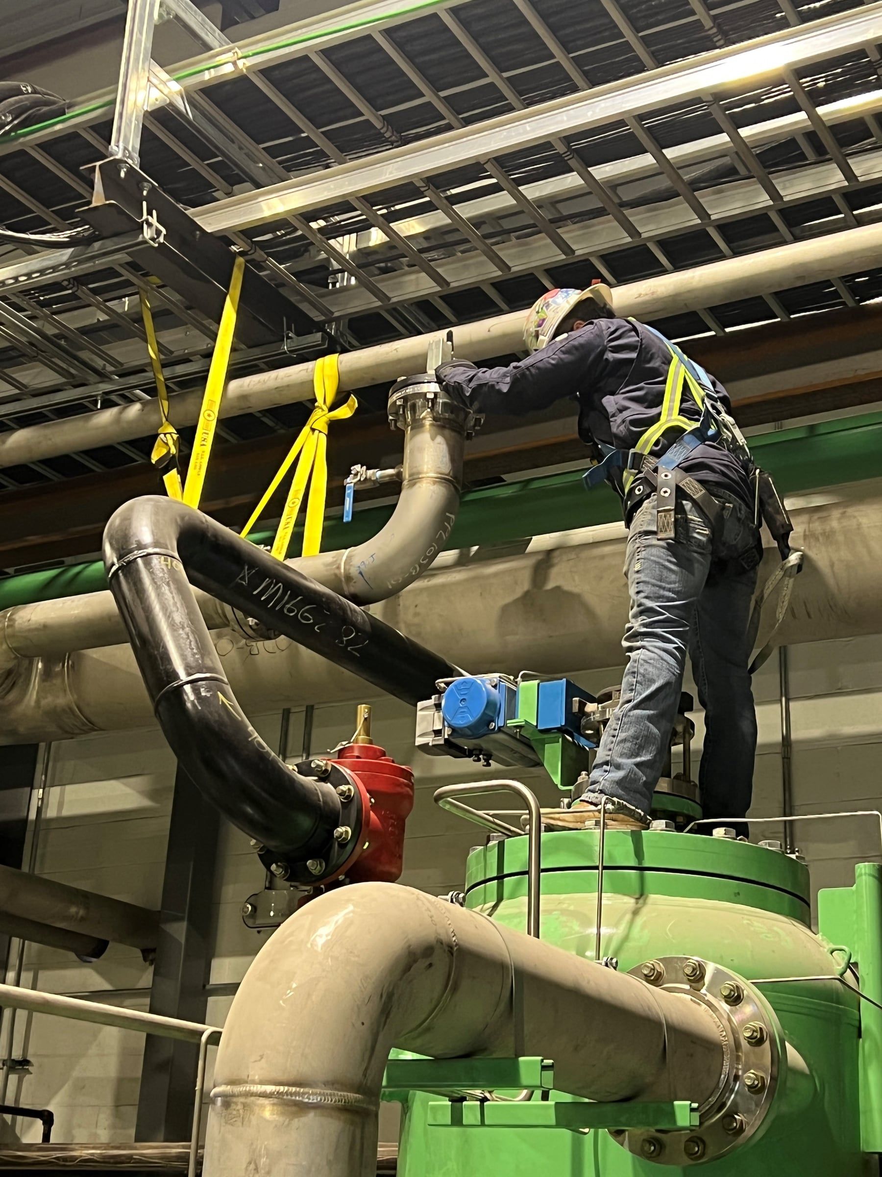 Crew member rigging a pipe spool overhead during test preparation