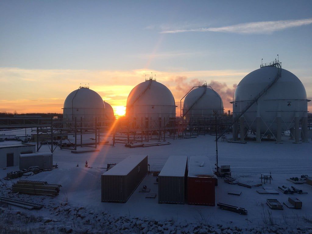 Storage spheres silhouetted against a sunrise