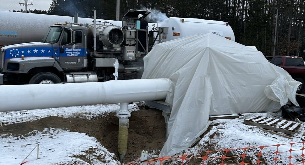 Tented pipe section and pumper unit during a winter drying job