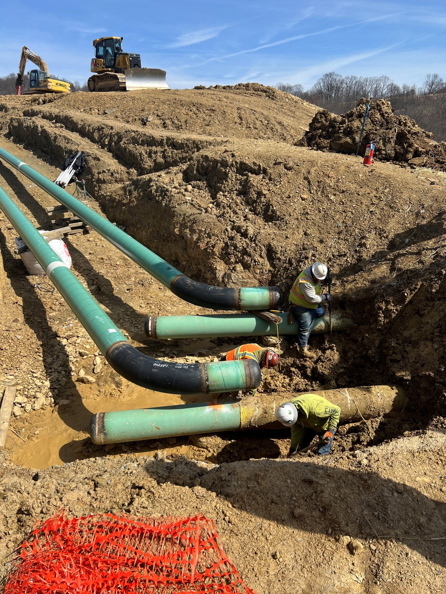 Coated 20 inch line sections staged in an open trench on a graded right of way